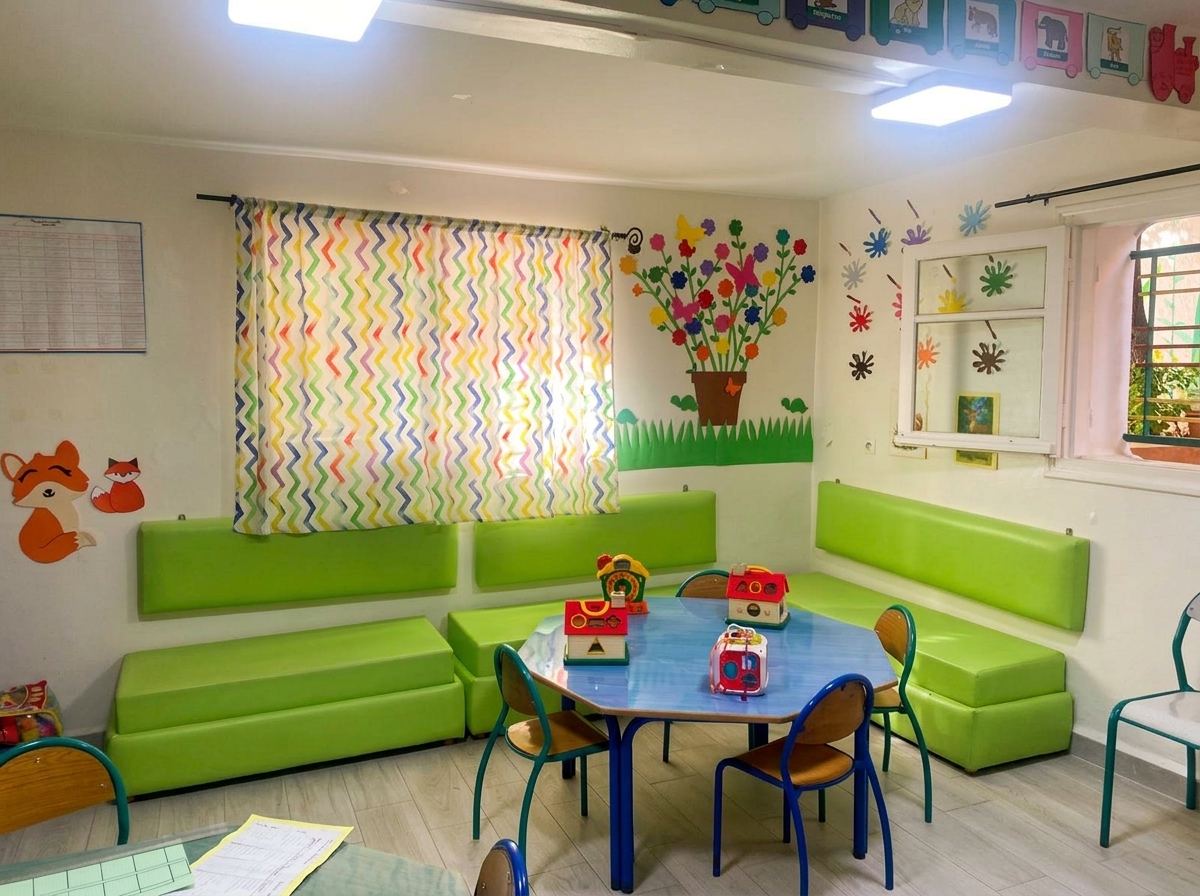 Classe de maternelle lumineuse avec banquettes, tables rondes et jeux d'éveil