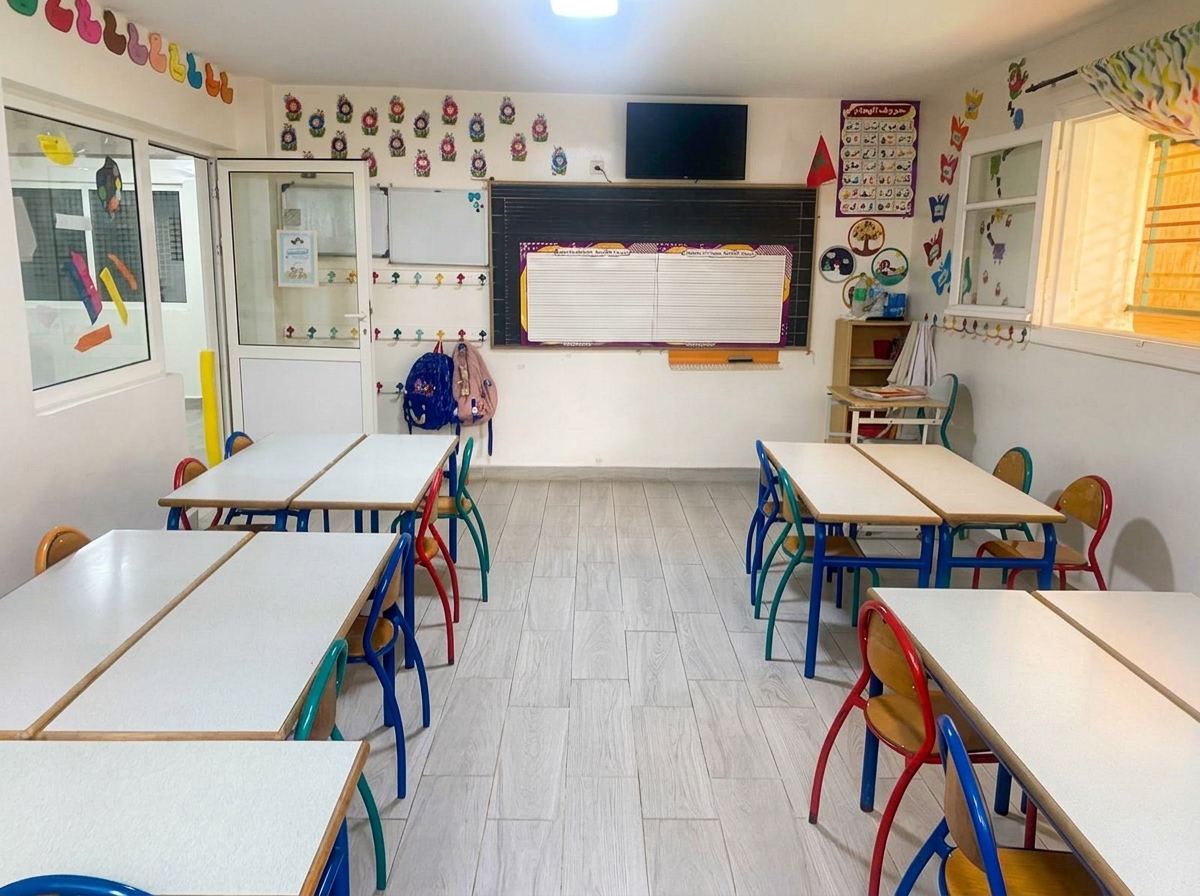 Salle de classe du primaire avec tableau, pupitres et affichages en arabe et en français
